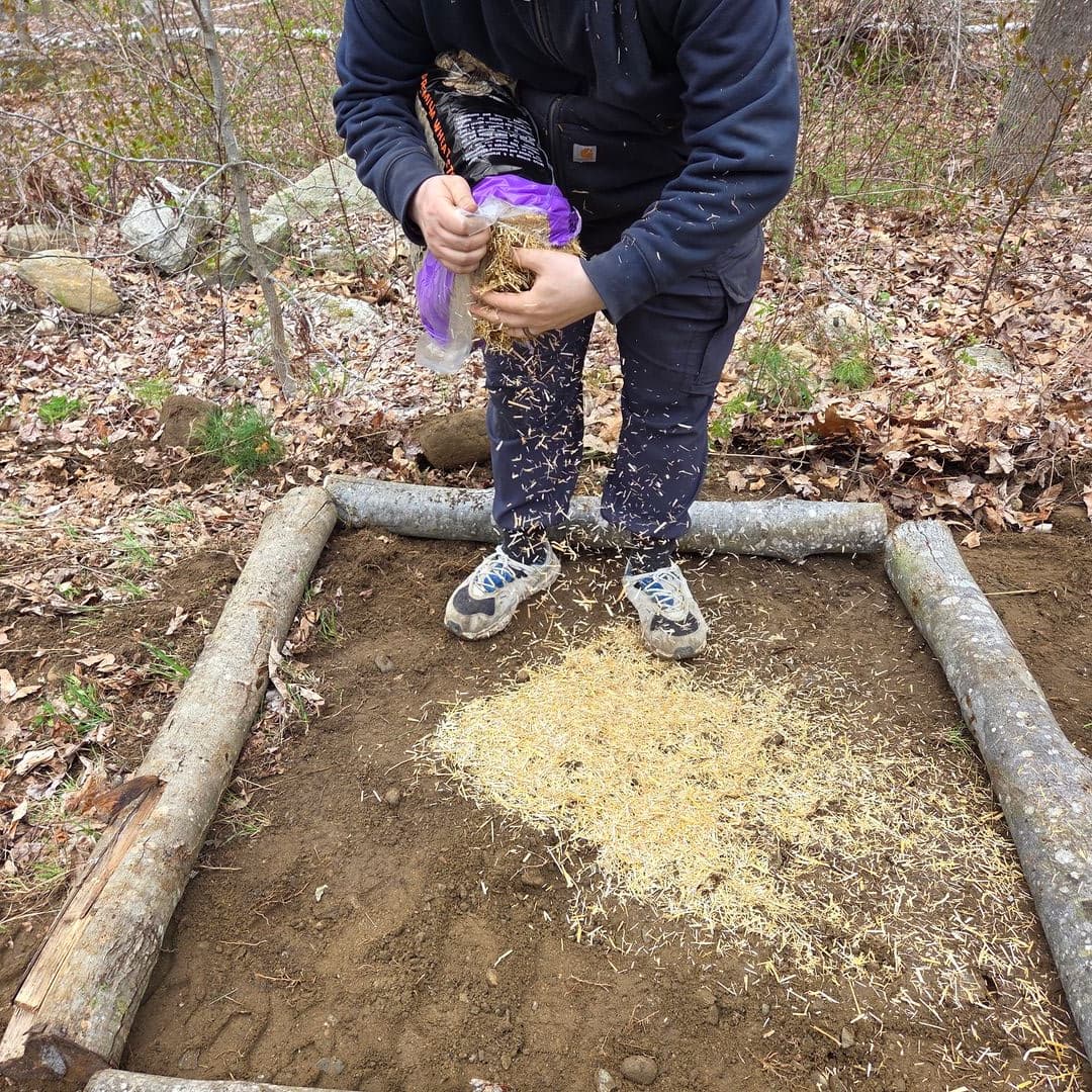Spreading straw inside the log-framed bed as a base layer